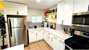 A modern kitchen with white cabinets, stainless steel appliances, and a wooden countertop. - Join Us For A Fiesta! - Central San Antonio (San Antonio)