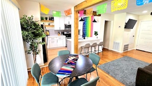 A modern kitchen with white cabinets, a microwave, and a coffee machine. There is a dining area with a round table and chairs, and a gray rug on the floor. - Join Us For A Fiesta! - Central San Antonio (San Antonio)