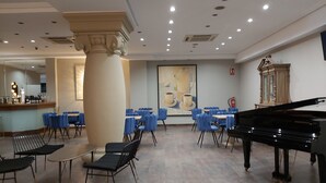 A spacious room with a grand piano, blue chairs, and a large painting on the wall. - Micampus Burgos Centro (Burgos)