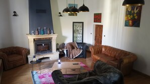 Ein Wohnzimmer mit Kamin, Ledersofas, einem Couchtisch und hängenden Pendelleuchten.