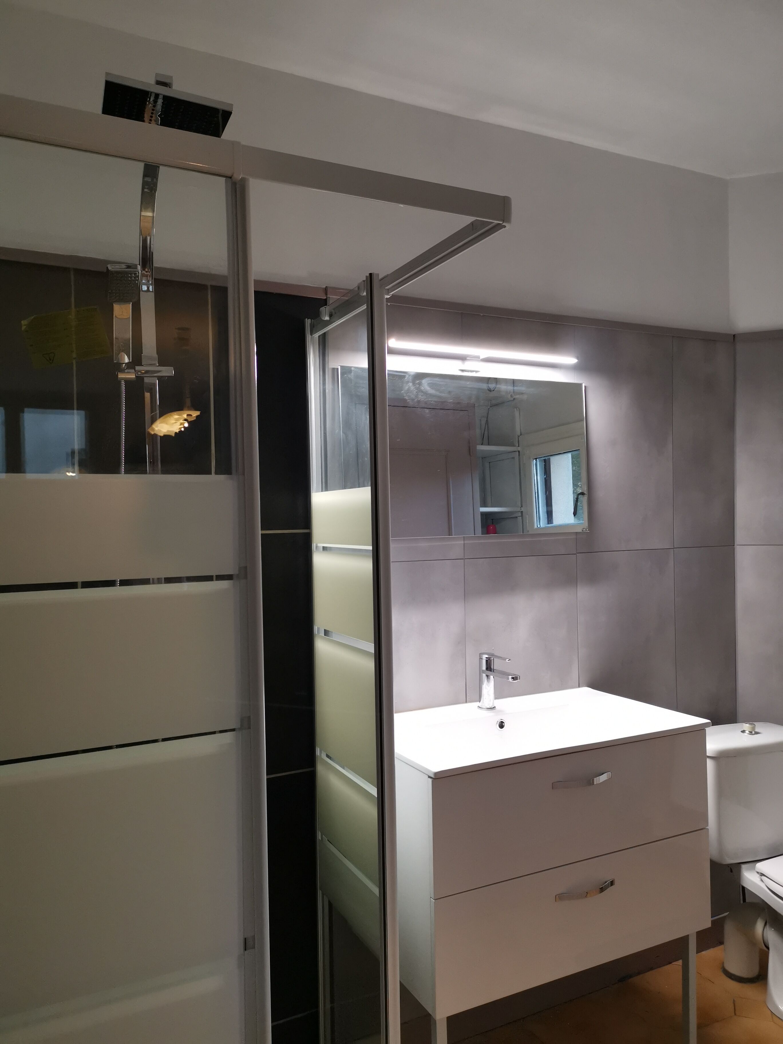 A modern bathroom with a white sink, a mirror, and a toilet.