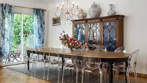 Ein Esszimmer mit Holztisch, klaren Stühlen, einer Chandelier und einem Schrank mit dekorativen Vasen.