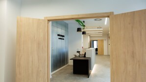 A modern hallway with wooden doors, a black desk, and a white partition. - Micampus Residencia Estudiantes Burjassot Parque (Burjasot)
