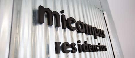 A corrugated metal wall with the words "micampus residencias" in black letters.