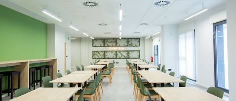 A conference room with long tables and chairs, a green accent wall, and a large window.