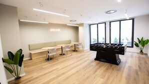 A modern indoor space with a foosball table, seating area, and large windows. - Micampus Residencia Estudiantes Burjassot Parque (Burjasot)