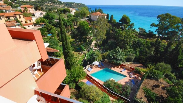 Zona residencial con piscina rodeada de árboles y vista al mar.