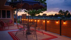 Eine Außenpatio mit Tisch und Stühlen, einem überdachten Bereich und Blick auf ein Sportfeld.