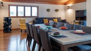 Ein modernes Wohnzimmer mit Essbereich, Holzboden, großem Fenster und einem Flachbildfernseher.