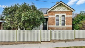 A two-story house with a brick facade and a white picket fence. - Best Nest on March. Firepit Cottage. Walk to CBD. (Orange)