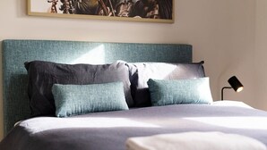 A neatly made bed with a grey and white duvet, two teal pillows, and a white throw blanket. - Best Nest on March. Firepit Cottage. Walk to CBD. (Orange)