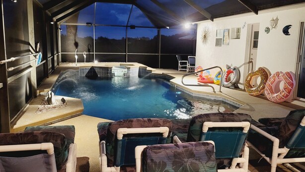 Una piscina coperta con lettini, giochi gonfiabili e vista sul cielo notturno.