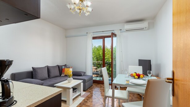 Ein modernes Wohnzimmer mit einer Couch, einem Couchtisch und einem Essbereich mit Stühlen und einem Glastisch.