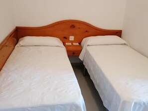 Uma cama de casal com cabeceira de madeira e roupa de cama branca.
