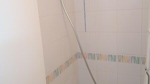 Un espace douche avec des carreaux blancs et une bordure colorée.