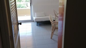 A room with a white sofa and a chair, a tiled floor, and a door leading outside. - Apartment 2/4 sea view (L'Estartit)