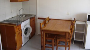 A compact kitchen with a built-in washing machine, a sink, and a dining table with chairs. - Apartment 2/4 sea view (L'Estartit)