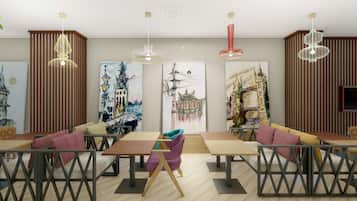 A modern dining area with wooden tables and metal chairs, featuring artwork on the walls and pendant lighting.