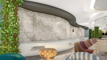 Ein moderner Empfangsbereich mit einer gebogenen Wand, einer Marmor-Theke und Grünpflanzen. Es gibt gepolsterte Sitzbereiche mit einem gemusterten Teppich.