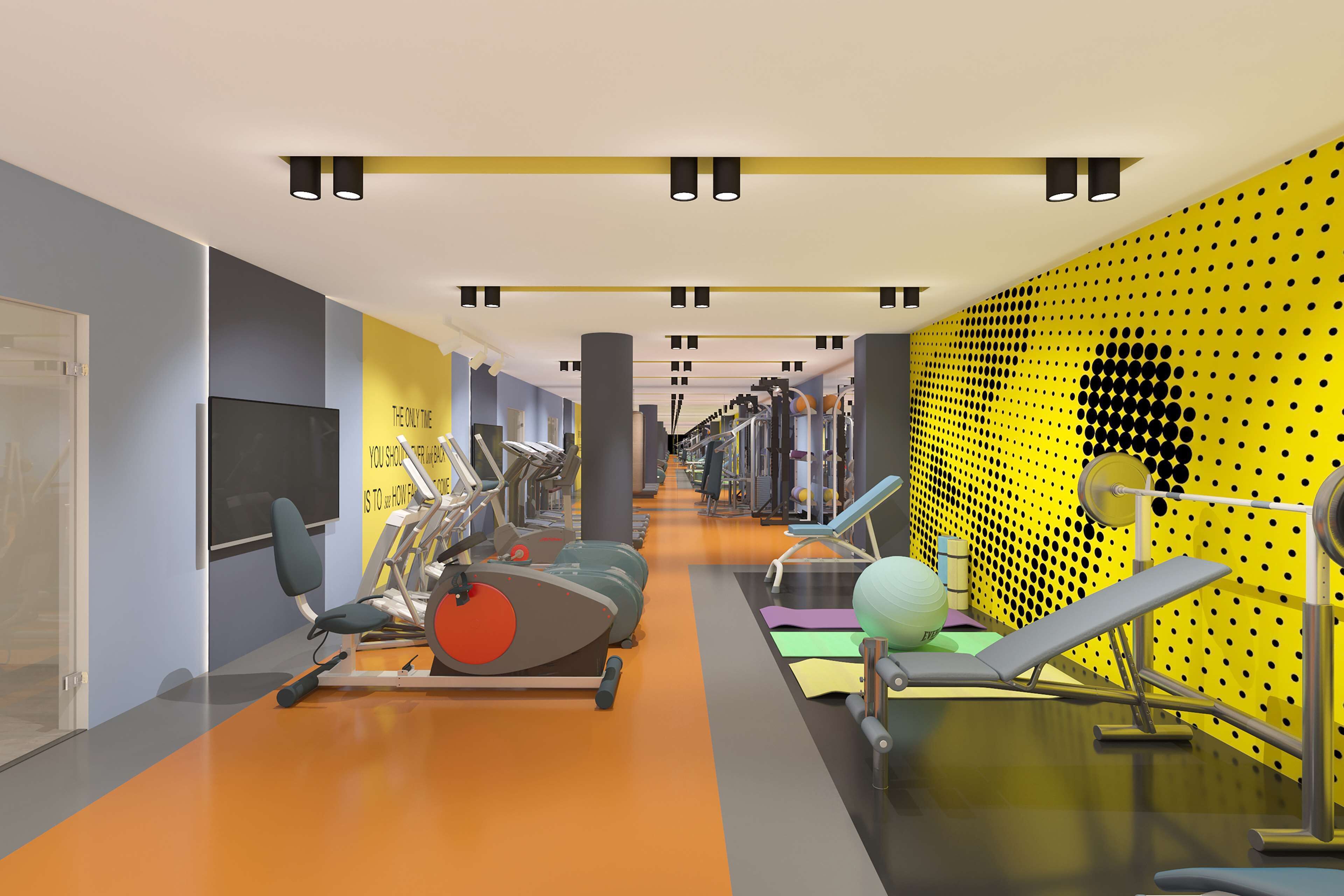 Ein modernes Fitnessstudio mit unterschiedlichen Trainingsgeräten, einem großen Spiegel und motivierenden Wandbildern.