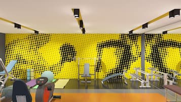 A modern gym with various exercise equipment, a yellow patterned wall, and a large mirror.