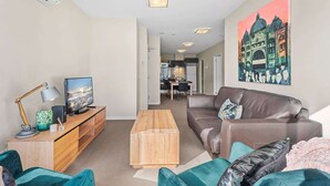 A modern living room with a TV, wooden coffee table, and a brown leather sofa. - Chic Inner City Convenience, with Secure Parking (South Melbourne)