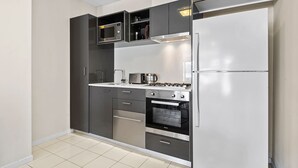 A compact kitchen with a built-in microwave, stove, oven, and refrigerator. - Chic Inner City Convenience, with Secure Parking (South Melbourne)