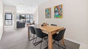 A modern meeting room with a wooden table, black chairs, and two colorful abstract paintings on the wall. - Chic Inner City Convenience, with Secure Parking (South Melbourne)