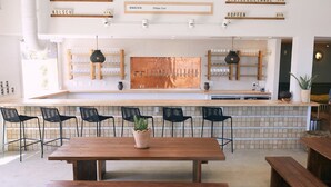 A modern kitchen with a central island, black bar stools, and a wooden table with benches. - Covered patio, fenced back yard, open floor plan (North Charleston)