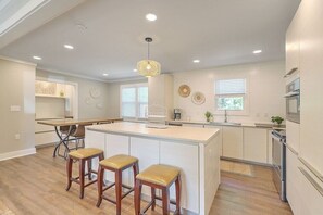 A modern kitchen with a central island, bar stools, and built-in appliances.