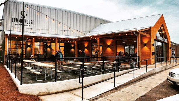 A building with a covered outdoor seating area, a sign reading "COMMONHOUSE ALEWORKS," and a car parked in front. - Covered patio, fenced back yard, open floor plan (North Charleston)