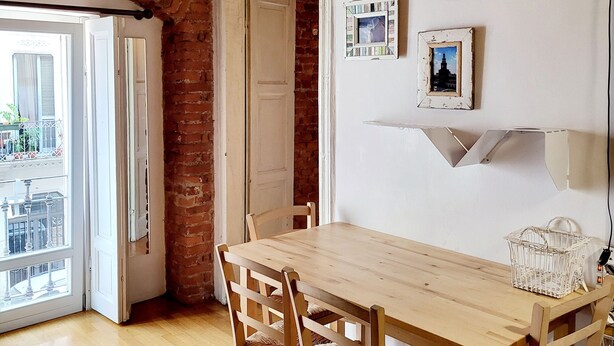 Une table à manger en bois, des chaises, un luminaire suspendu et des tableaux encadrés accrochés au mur.
