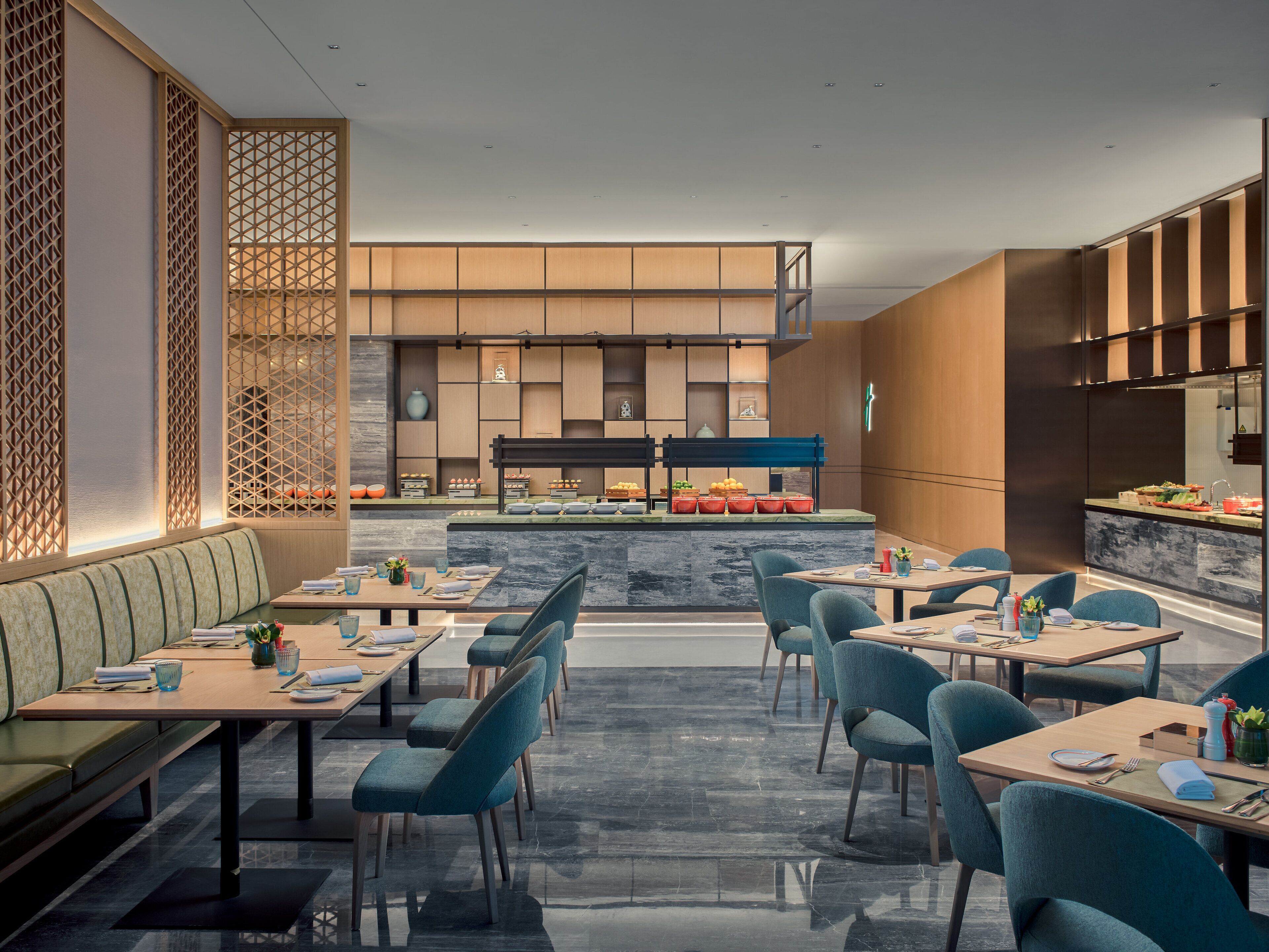A modern restaurant with a central counter, seating area with tables and chairs, and decorative elements.