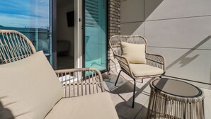 A balcony with wicker furniture, a glass door leading to an interior space, and a tiled wall. - 30 Cliff Edge (Newquay)