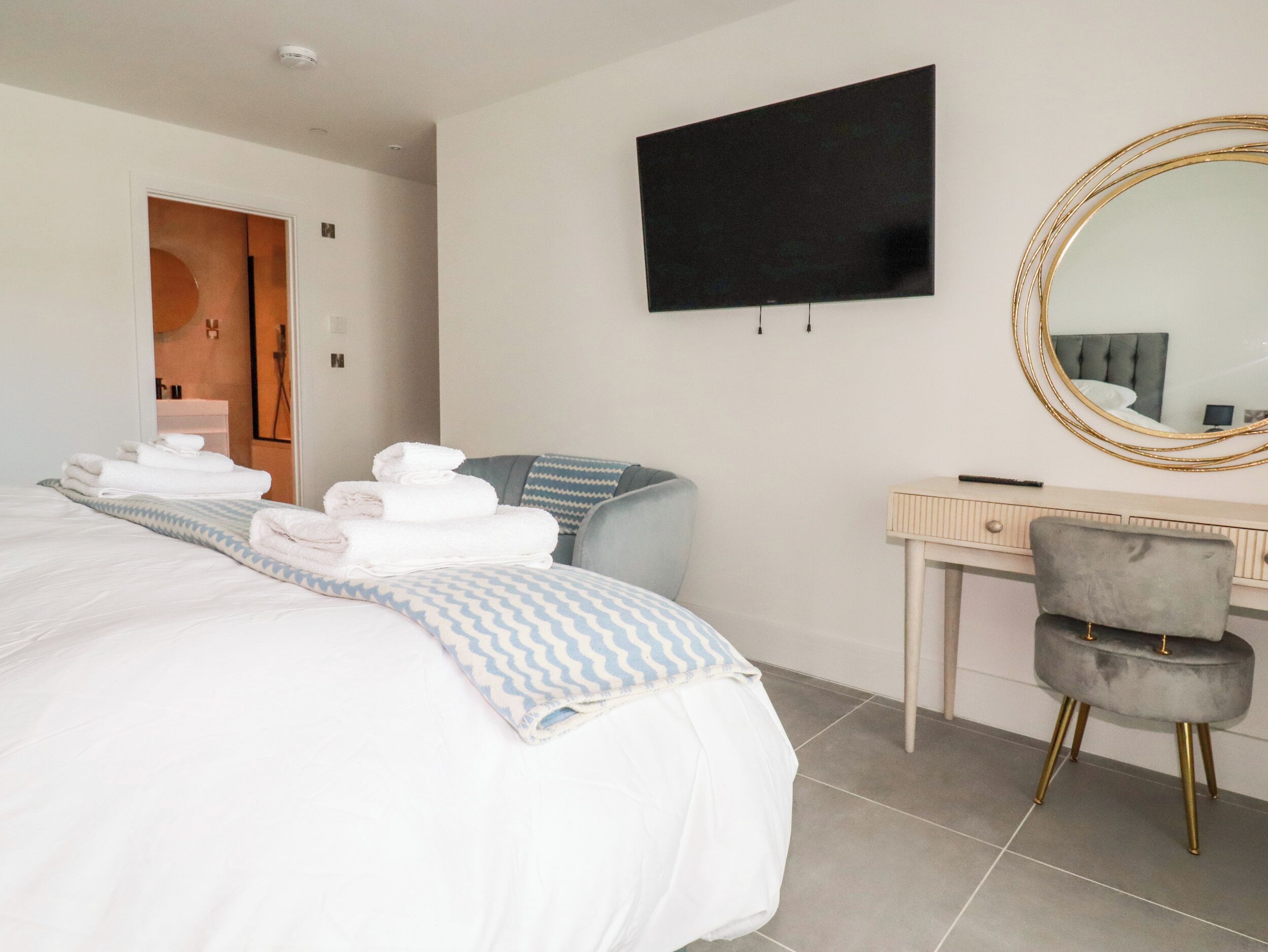 Ein Hotelzimmer mit einem Bett, einem Schreibtisch, einem Stuhl, einem Fernseher und einem Spiegel.