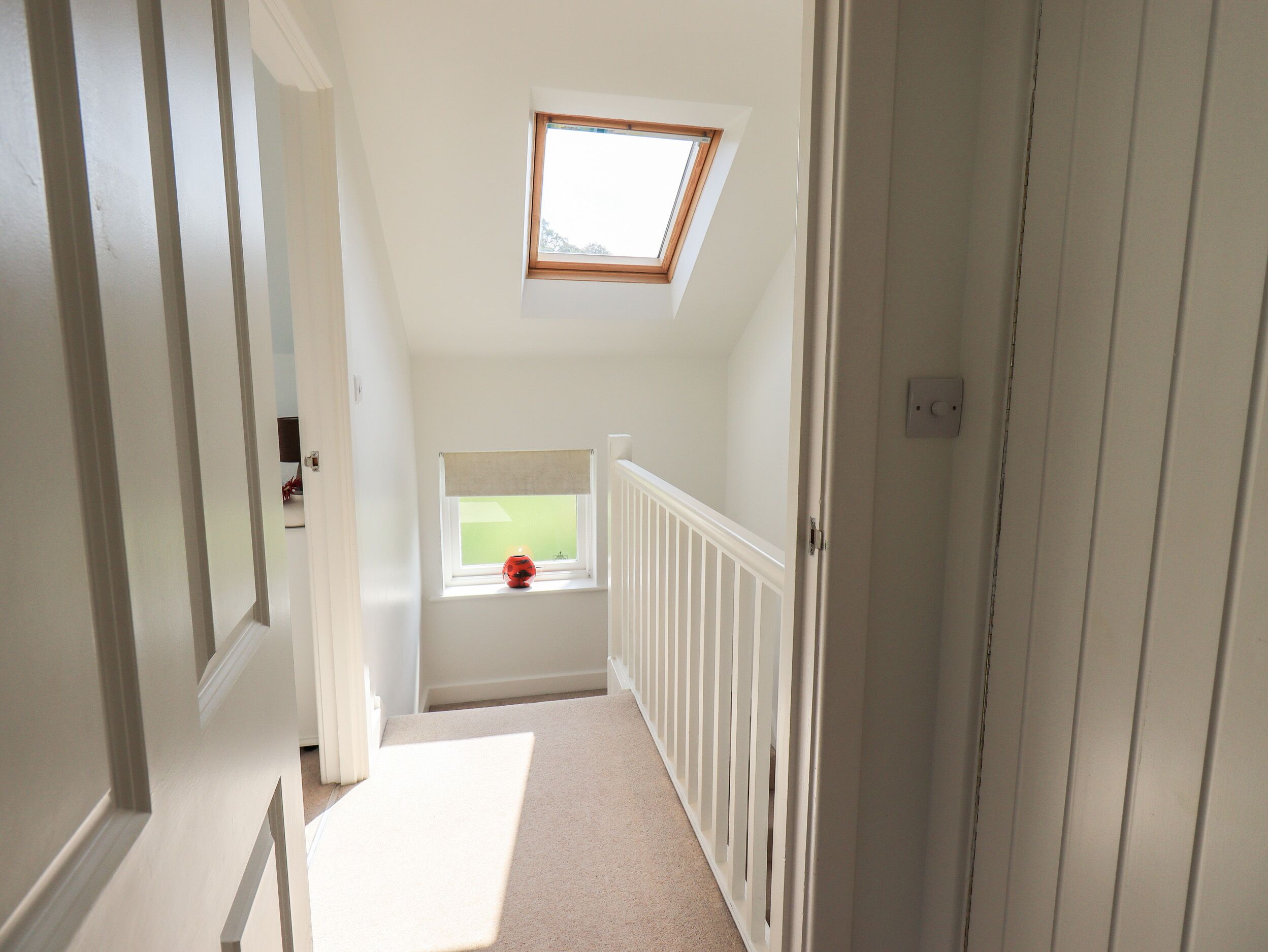 A narrow hallway with a sloped ceiling and a skylight.