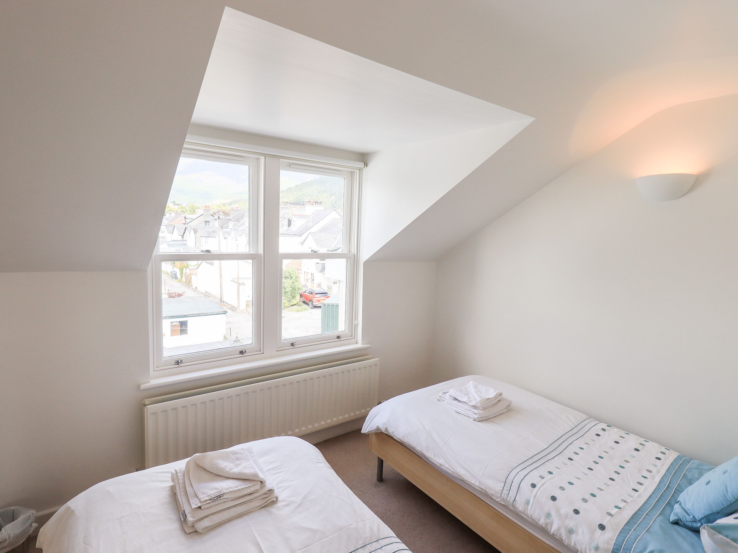 A bedroom with a skylight, a radiator, and a bed with a blue pillow.