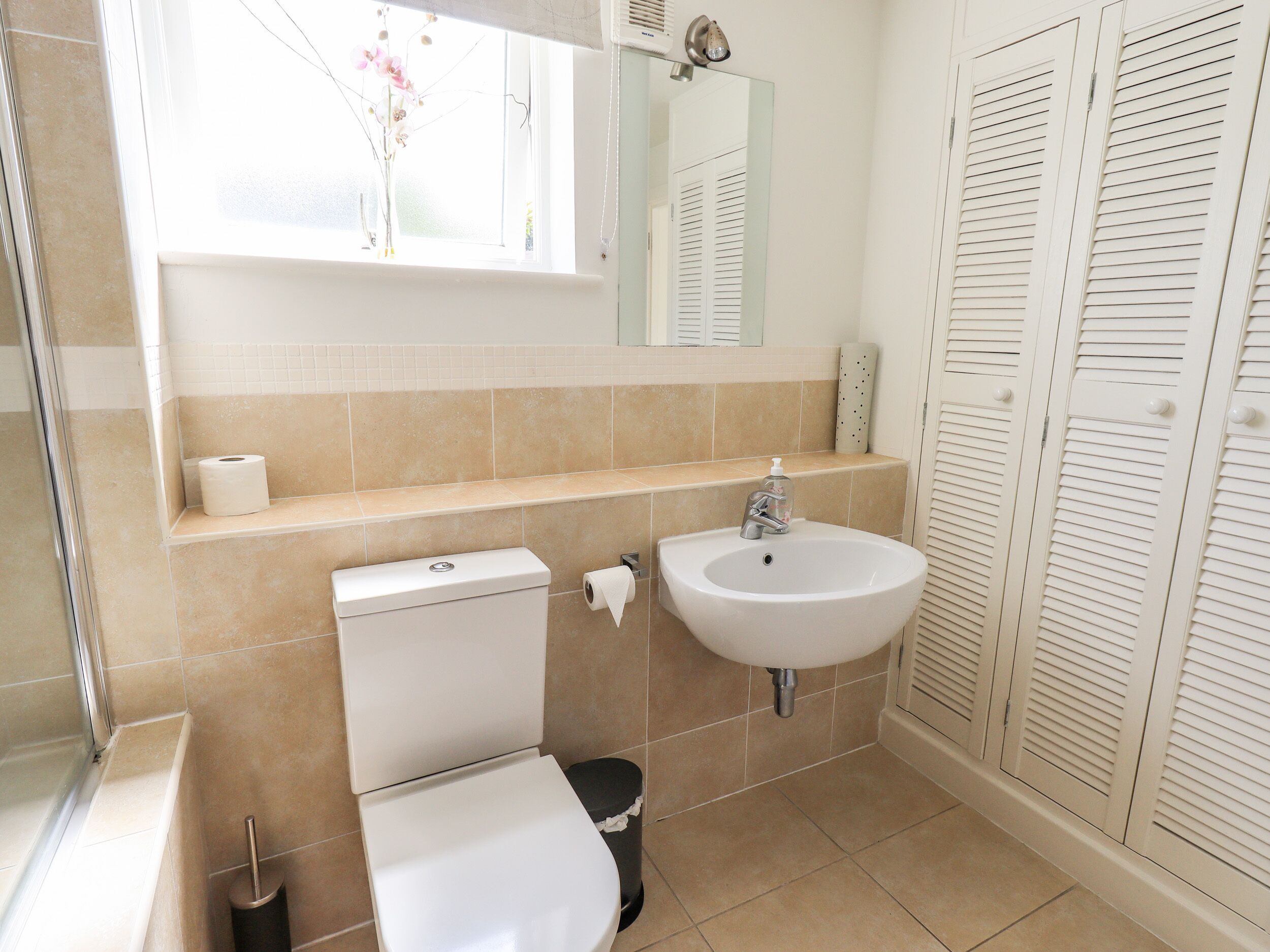 Un baño con inodoro, lavabo y armarios de almacenamiento.