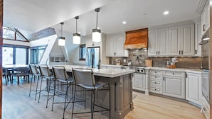 A modern kitchen with a large island, bar stools, and a skylight. - The Lodge at Mountain Village | Stunning Ski-In/Out Presidential Penthouse | A Nestique Property (Park City)