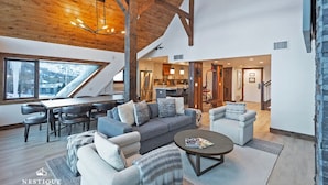 A spacious living area with a high ceiling, wooden beams, and a dining area with modern furniture. - The Lodge at Mountain Village | Stunning Ski-In/Out Presidential Penthouse | A Nestique Property (Park City)