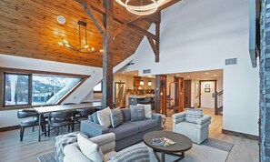 Ein geräumiger Wohnbereich mit hoher Decke, Holzbalken und einem Essbereich mit modernen Möbeln.