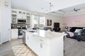 Enjoy cooking and relaxing in this spacious kitchen and living area, featuring a large island, oven, and comfortable seating.