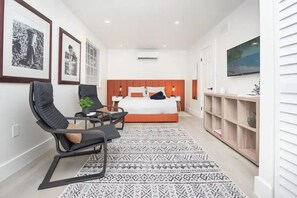 A modern hotel room with a large bed, a desk, a chair, a TV, and a bookshelf. - Stylish well decorated one bedroom apartment (Miami)