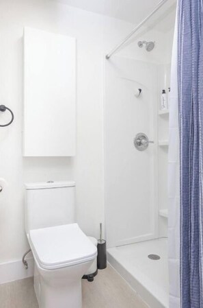 Un bagno moderno con il water, uno spazio doccia e un mobile bianco.