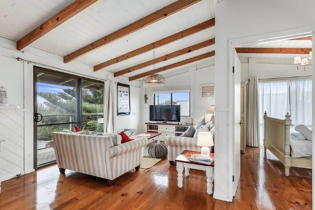 A spacious living room with a wooden ceiling, a television, a sofa, and a dining area.
