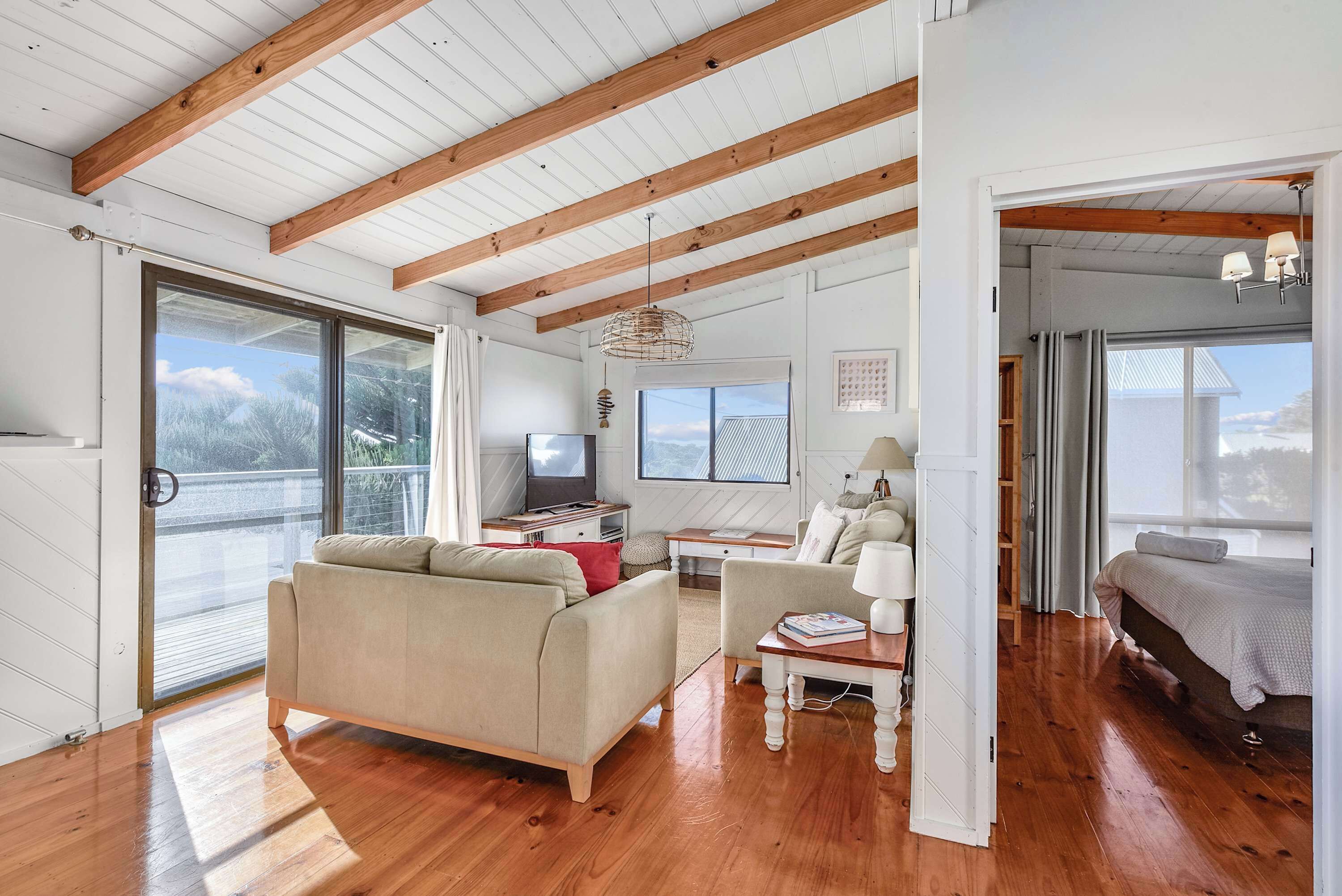 A spacious living area with a wooden ceiling, a sofa, a table, and a bed.