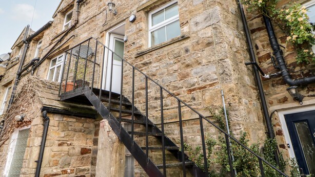 A stone building with a metal staircase leading to a balcony. - The Old Store, 2 Alpine Terrace (Richmond)