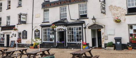 The Black Bull Hotel with a signboard, outdoor seating, and a cobblestone ground.