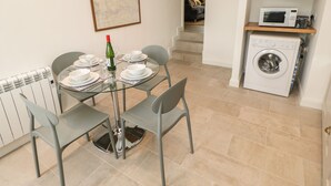 A dining area with a glass table, grey chairs, and a map on the wall. - The Old Store, 2 Alpine Terrace (Richmond)