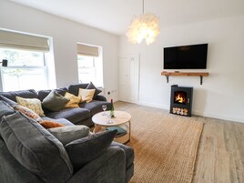A modern living room with a sofa, a fireplace, a television, and a window with blinds.